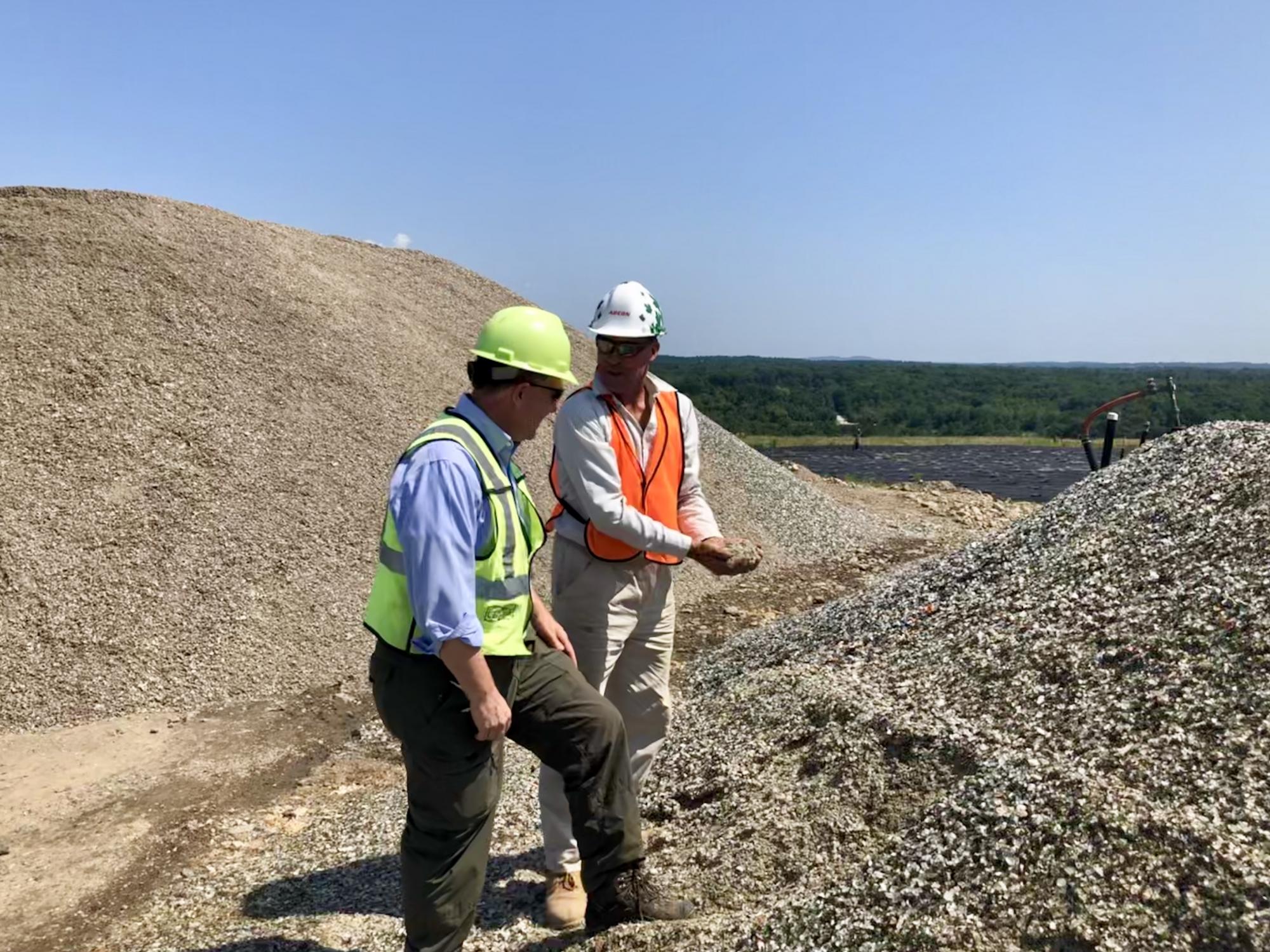 Bob Magnusson of Waste Management (left) and Ivar Martin, NRRA’s glass-crushing vendor, inspect PGA material at a Waste Management facility in Rochester, N.H. that serves as one of NRRA’s PGA host sites.